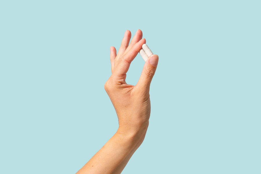 White Tend-2 pre-drinking capsules held against a blue background